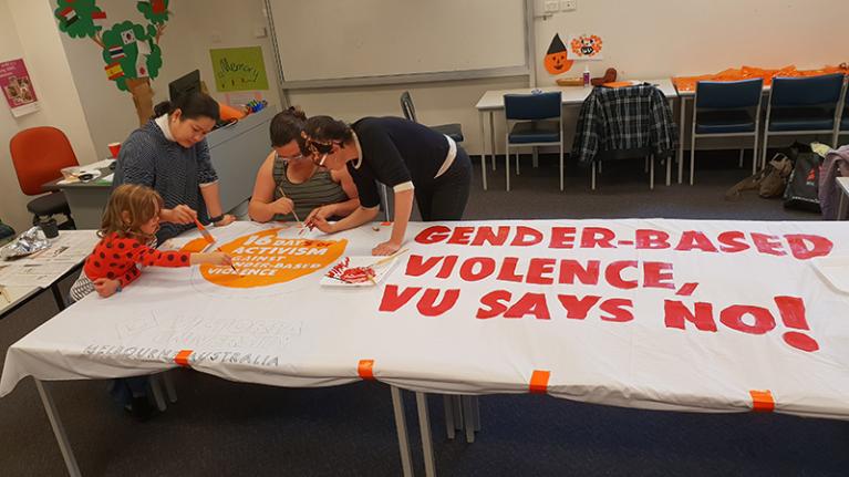 Child, women paint gender activism banner