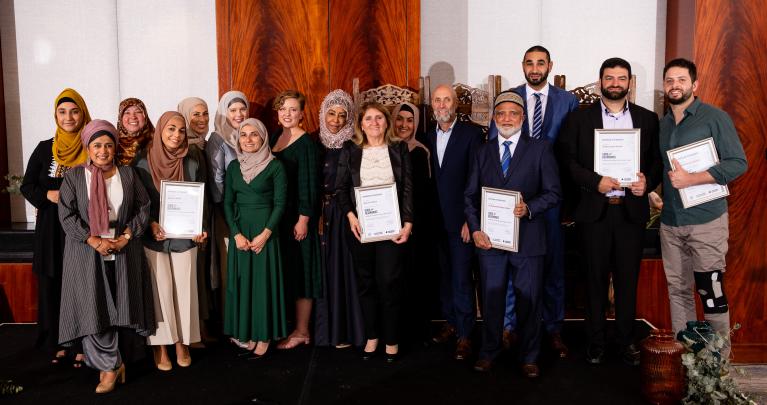 Marriage Mentors and Program staff stand on stage and smile with graduation certificates.