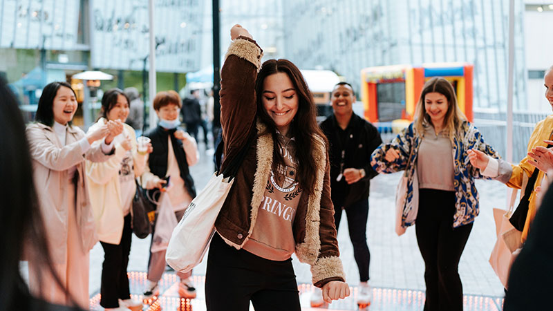 student busting a move on dancefloor at Block Party while 6 students cheer on