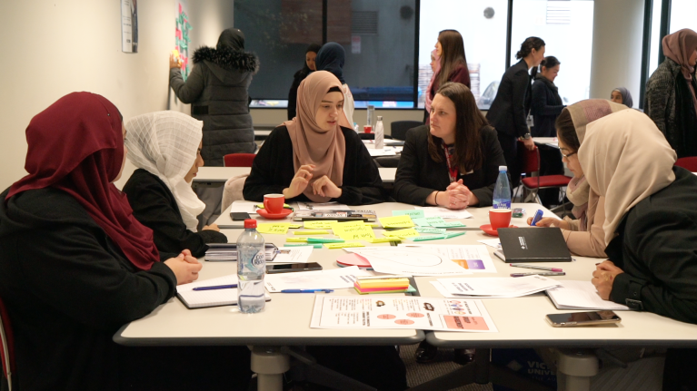 Program participants sitting around a table discussing their group project.