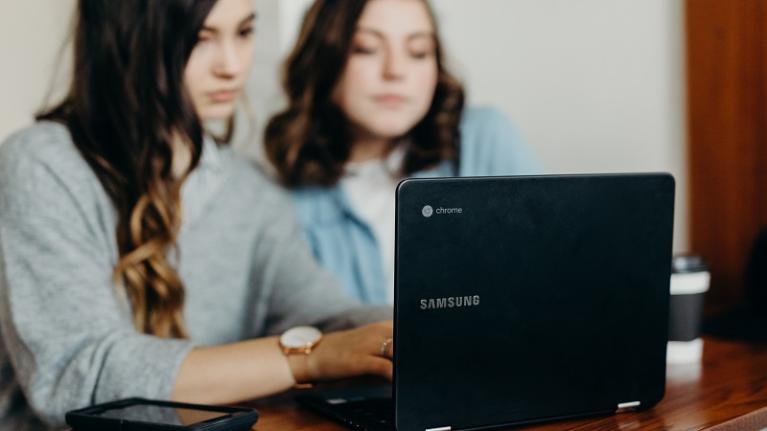 two teenage girls looking at laptop