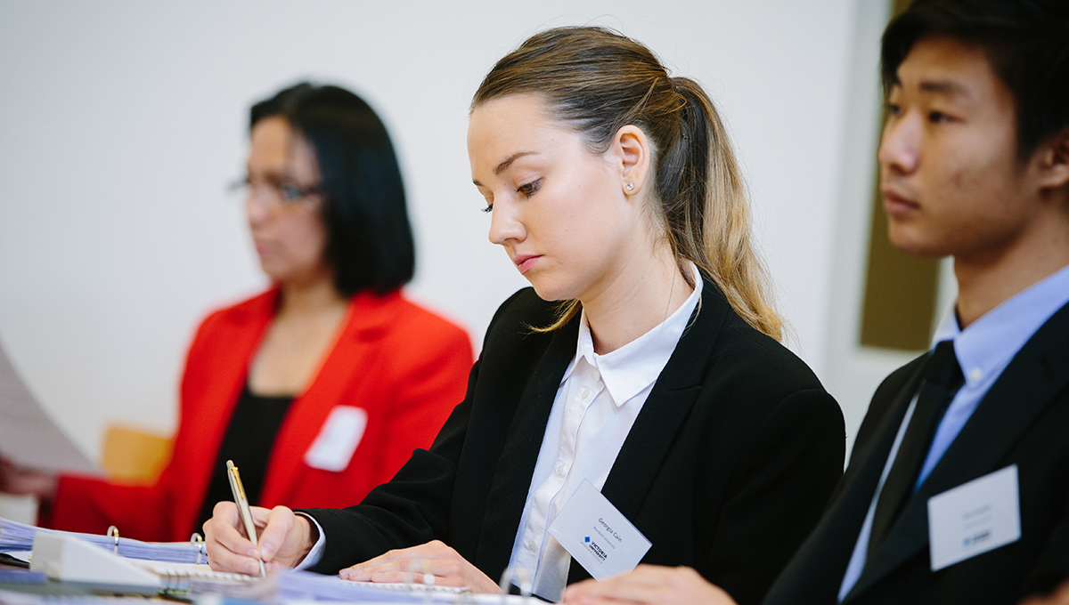 3 students seated, attentive during a MOOT.