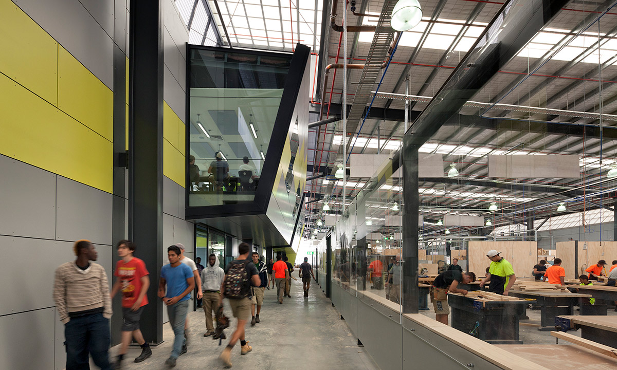 large, modern warehouse-style space with people in trade uniform, doing carpentry work