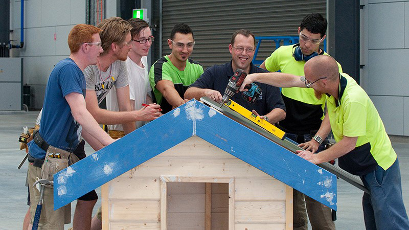 VU polytechnic construction students in the workshop gathered around a small construction they have built