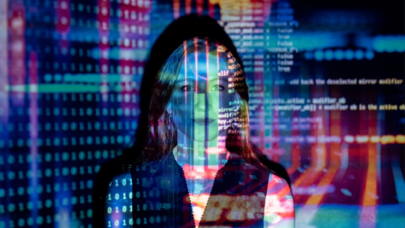 A woman with long red hair stands with data superimposed over her face.