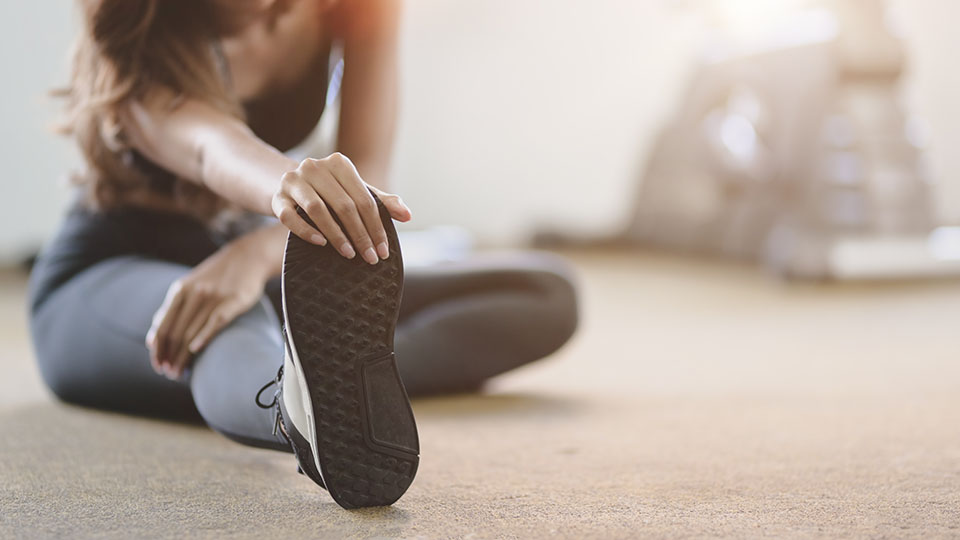 A woman stretching after playing sport.