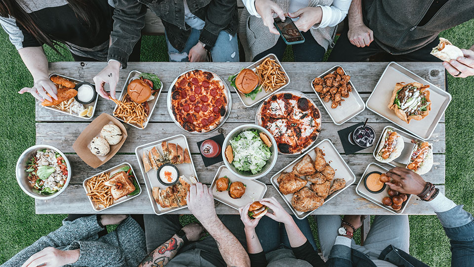 Birds-eye view of a group of people sit around a table, sharing food.