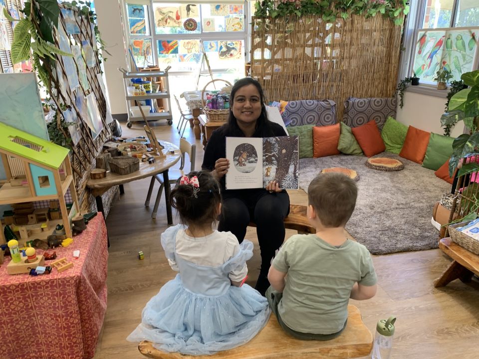 Pearl Jain is reading a book to two children in a childcare centre.
