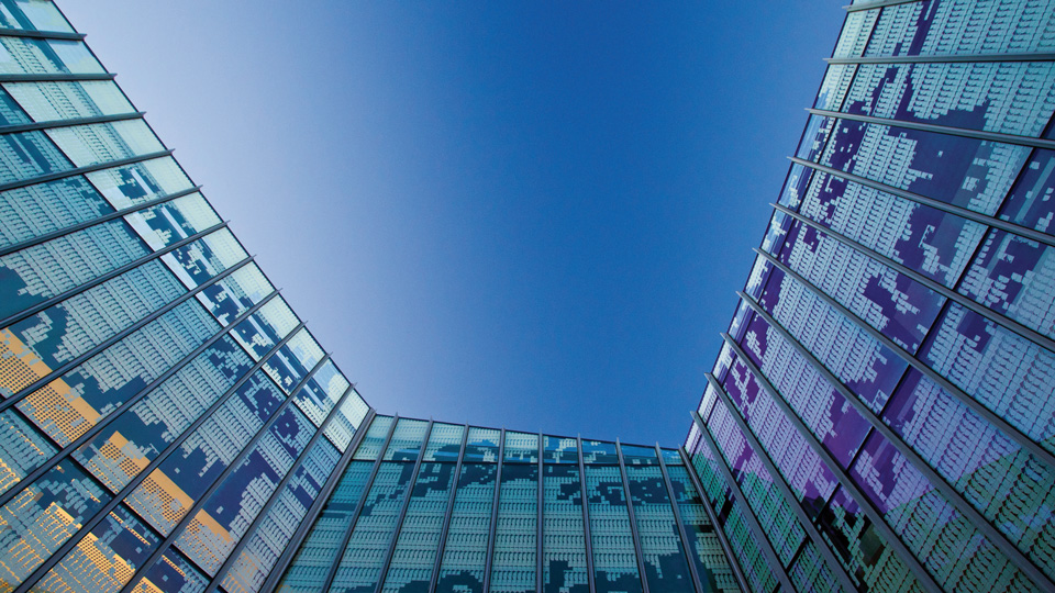 Looking up at the sky. To the edges of the photo are the walls of a glass building.