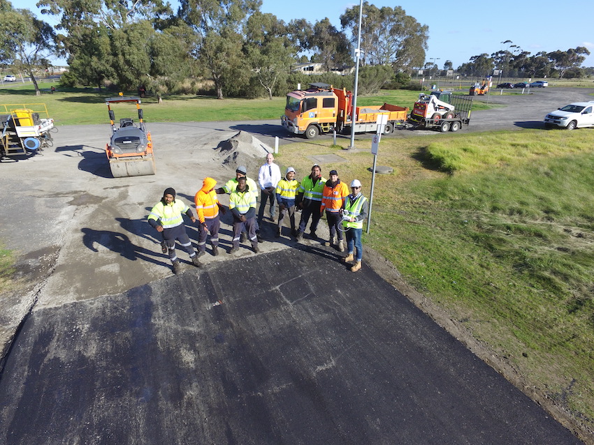 Workers and researchers standing on road made of recycled demolition waste.