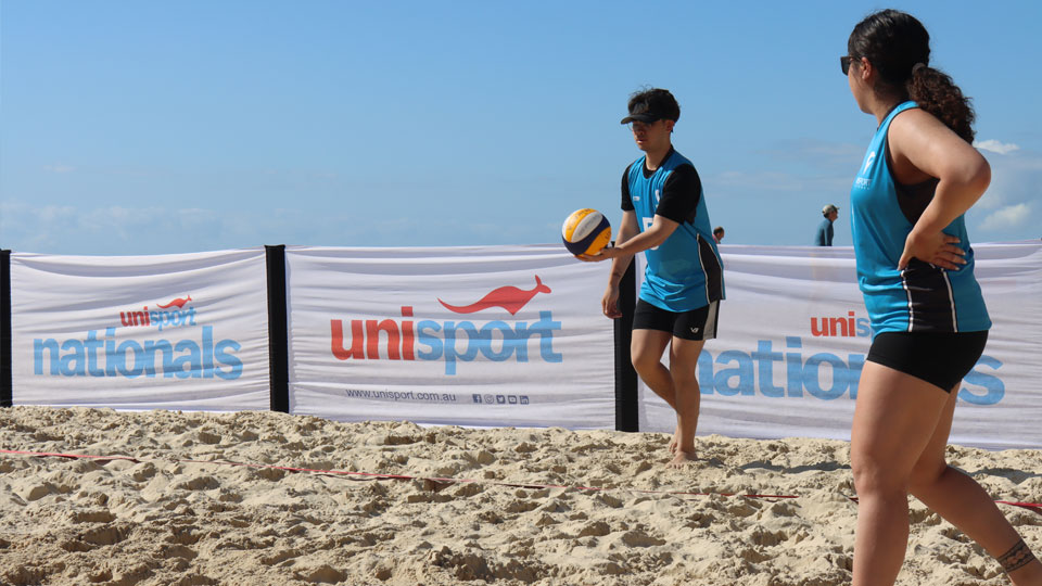 VU Vultures mixed volleyball team playing on the sand at the 2023 UniSport Nationals. Haans is about to serve the ball.