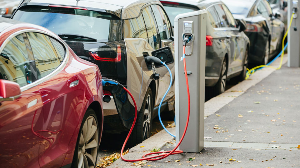 Photo of parked electric vehicles being charged at an EV charging station