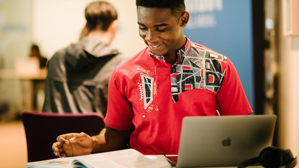student with laptop and book