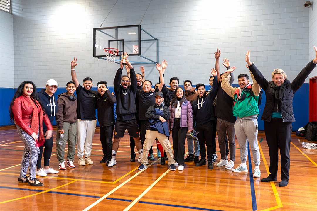 A group of people pose together in a basketball stadium.