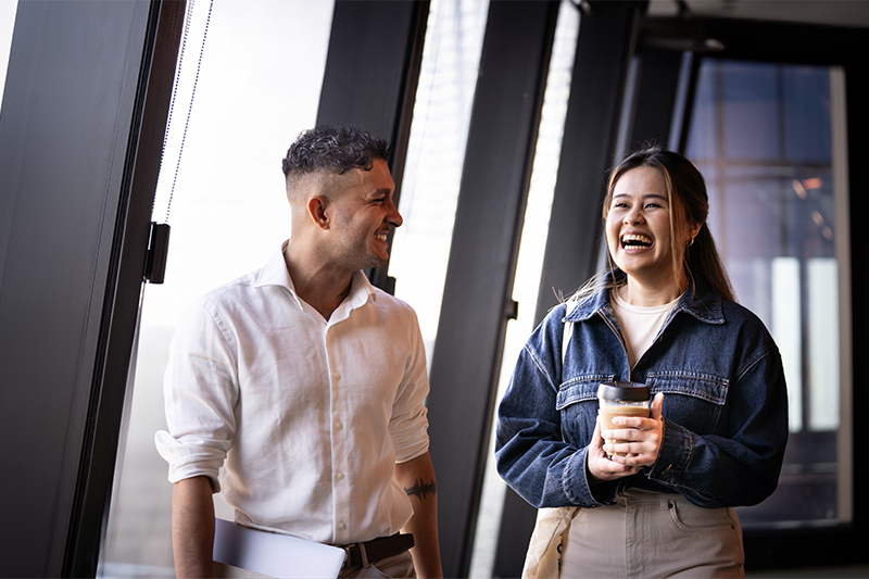 Two students walk down a hallway at VU's City Tower, one holding a cup of coffee.