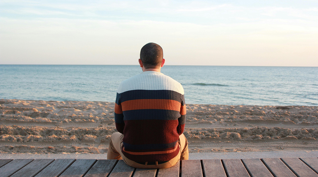 A man looks out over a lonely beach