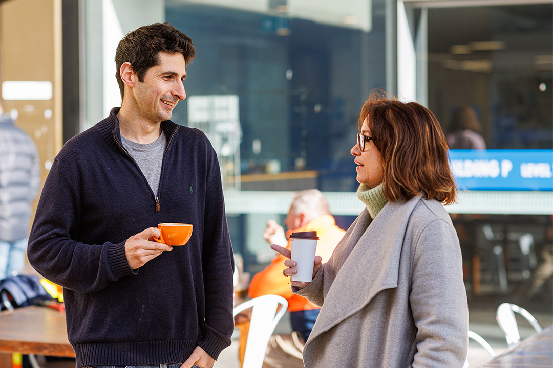 Staff members having coffee outside the Reading Room at Footscray Park campus.