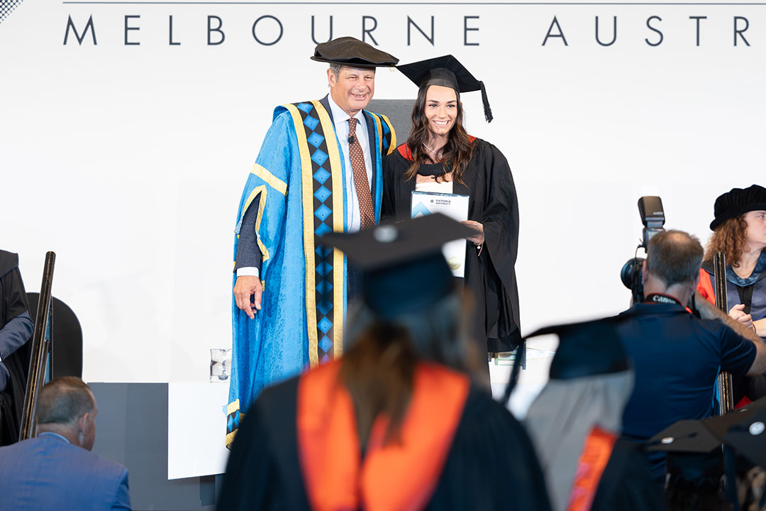 VU student posing for graduation photo with Chancellor Steve Bracks.