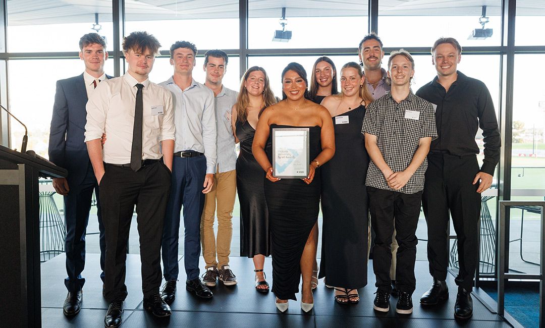 A group of young men and women in formal dresspose with an award