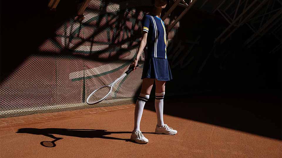 A tennis player stands on a clay court holding a racquet.