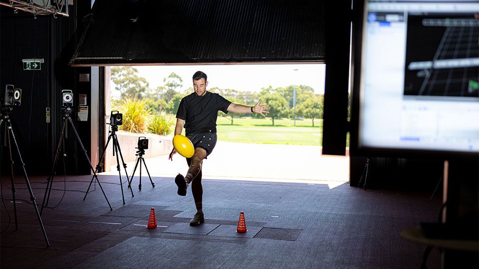 A person kicks a football, while being monitored for a research study at VU.