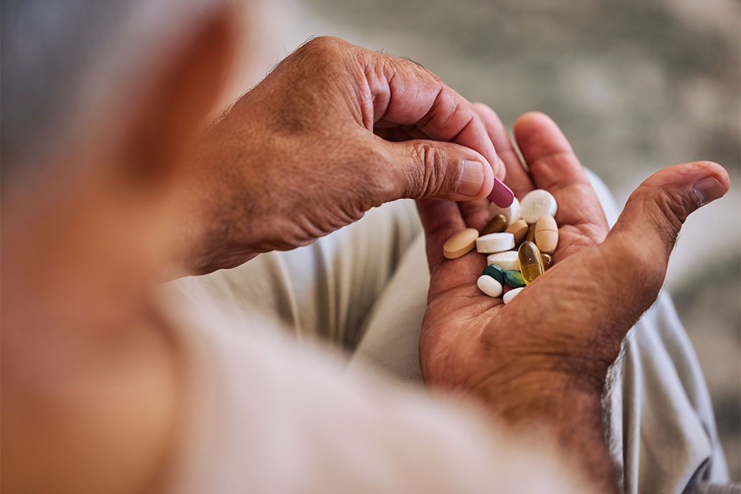 Hand holding a collection of different pills, to address chronic diease.