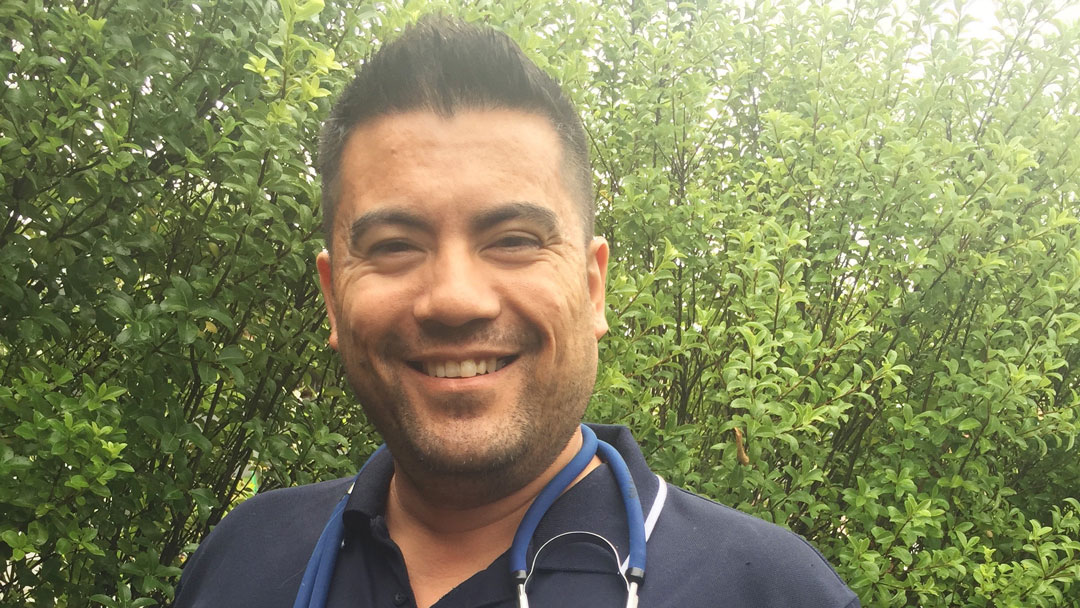 Shane Bautista standing outside with a stethoscope around their neck.
