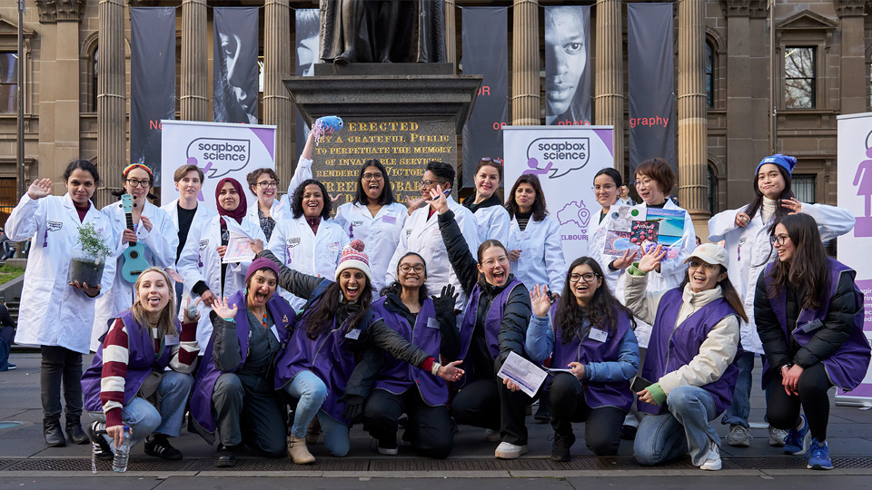 A large group of 20+ people and Dr Fernando at a Soapbox Science event outside Victorian State Parliament House. There is a happy atmosphere in the photo.