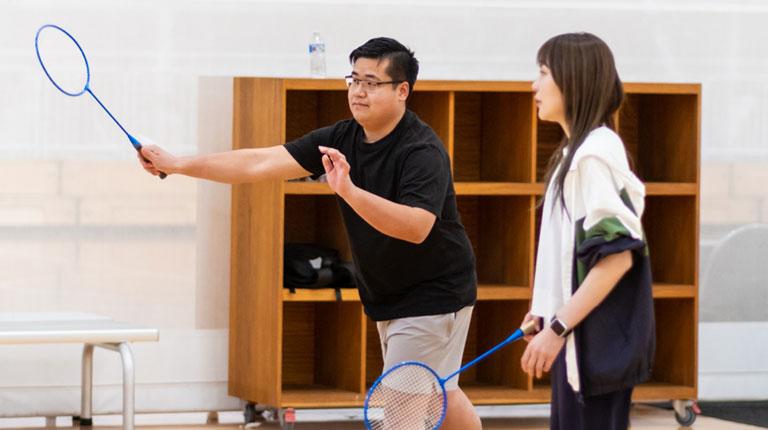Two students playing badminton.