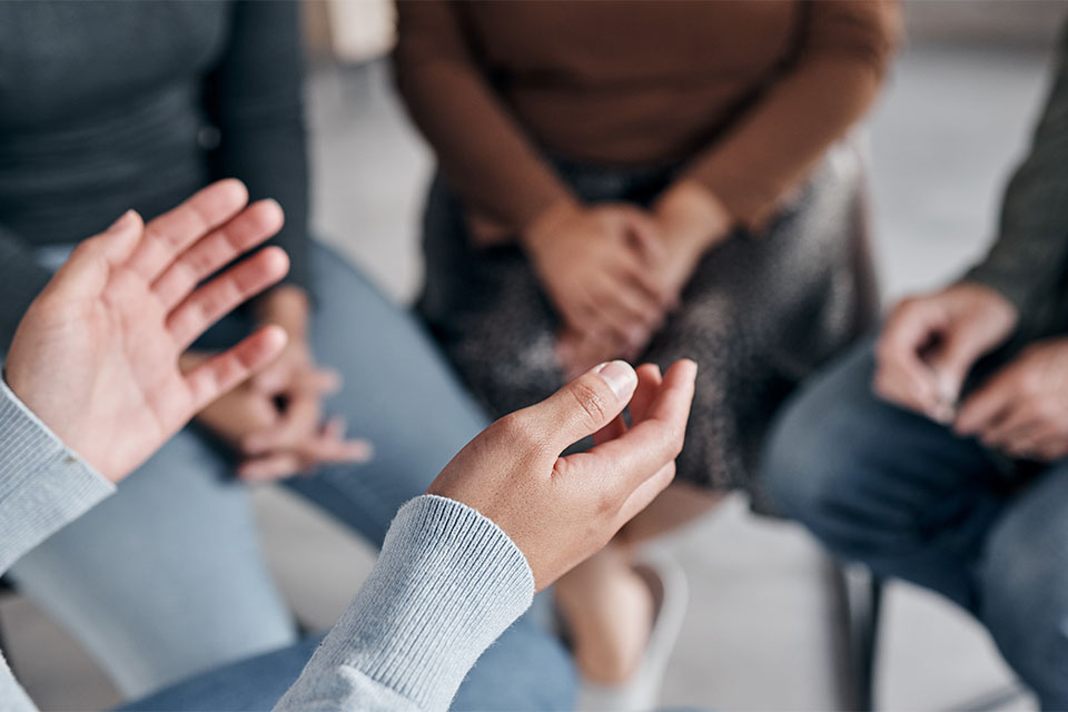 Group support session, person leading with outstretched hands.