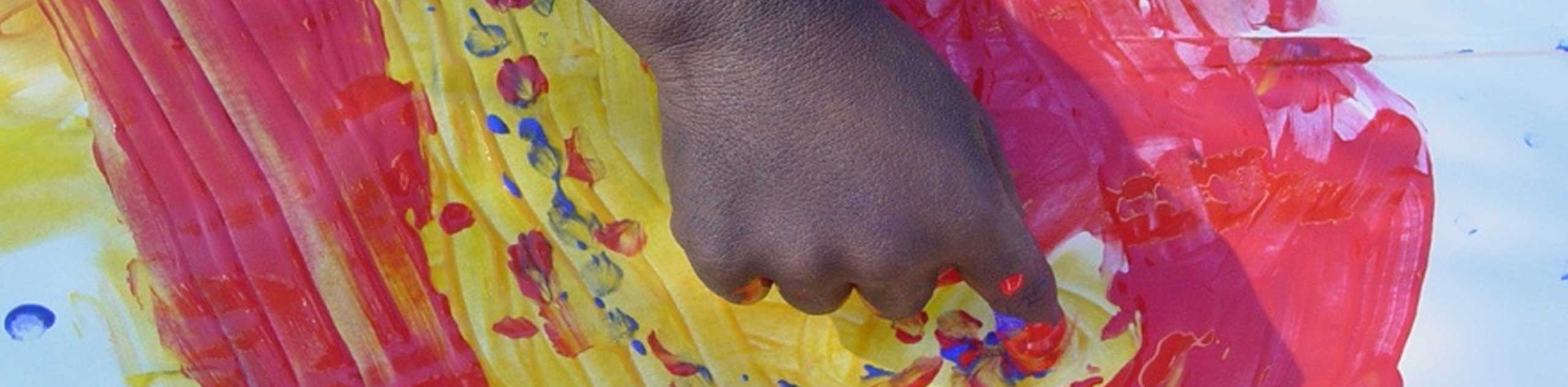swirl school student finger painting with yellow and red paint