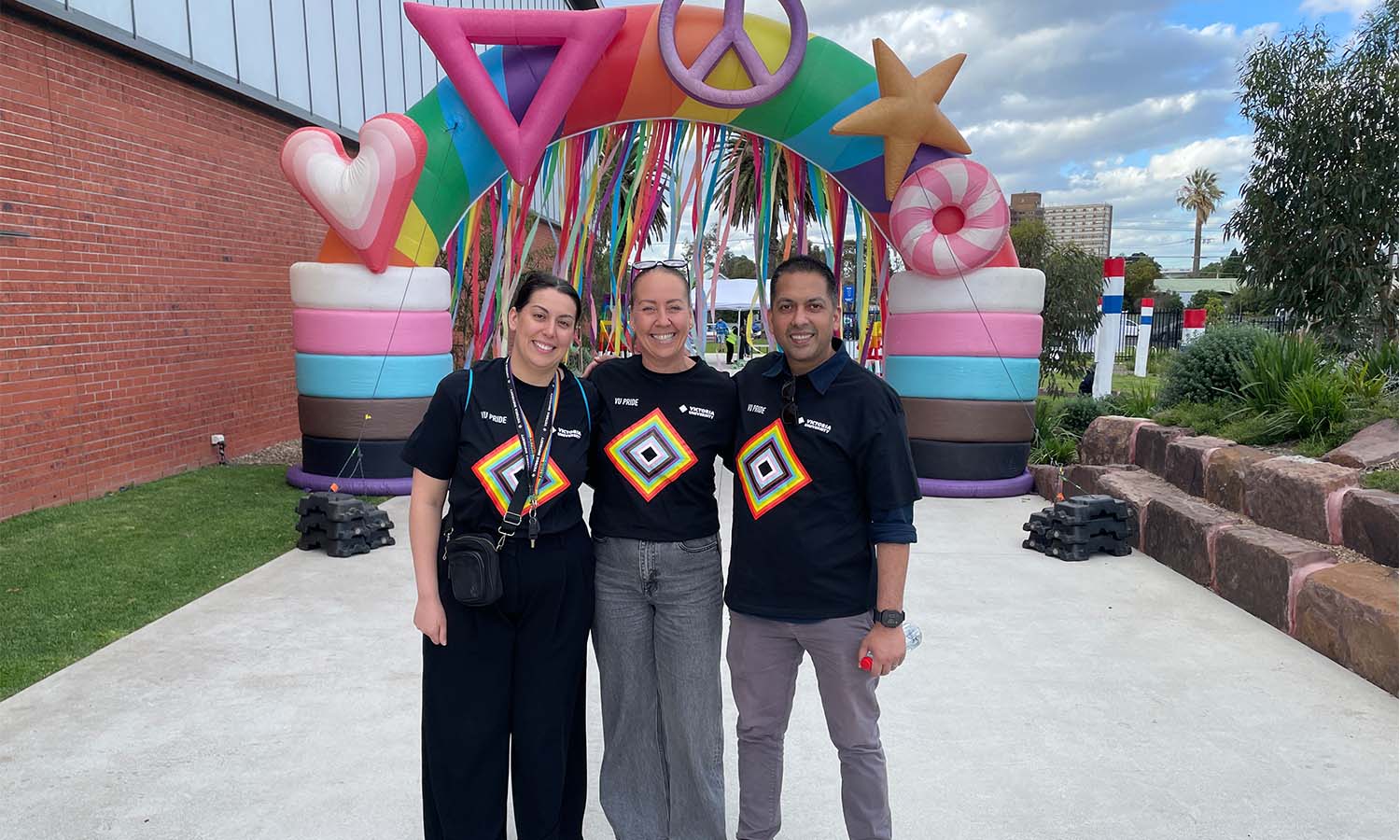 VU staff standing in front of rainbow display at football game