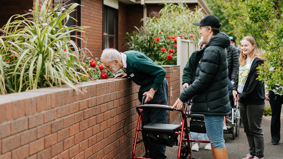A community walk with Doutta Gala Aged Care, a person stops to smell the spring roses