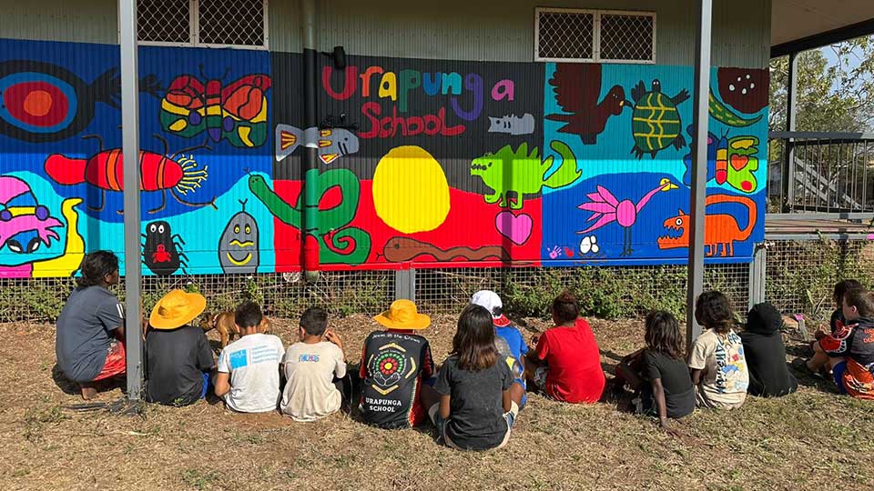 SWiRL Urapunga students seated in front of colourful mural