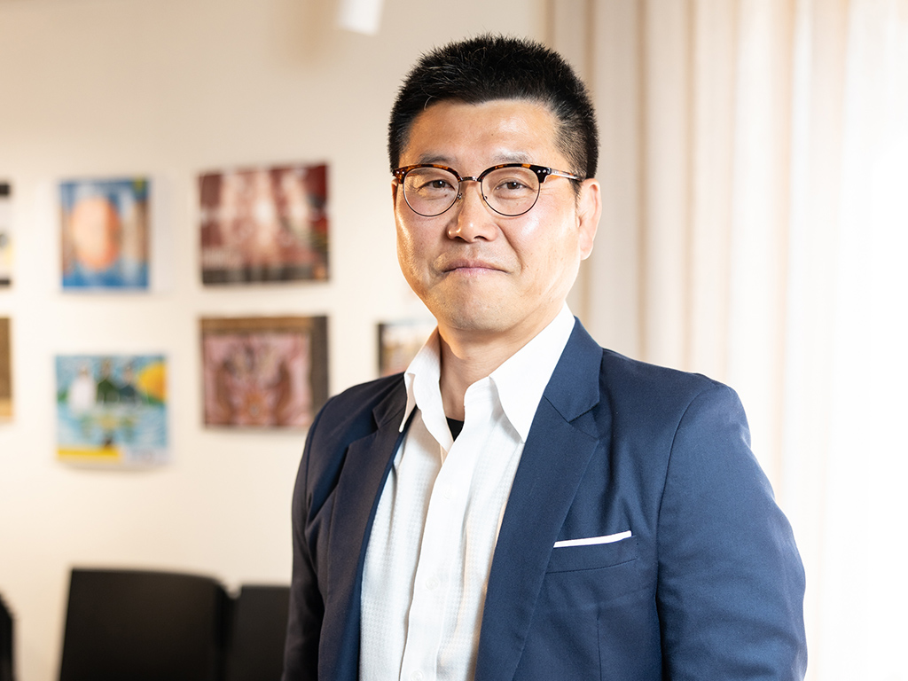 A man in a neat suit poses for a photo indoors