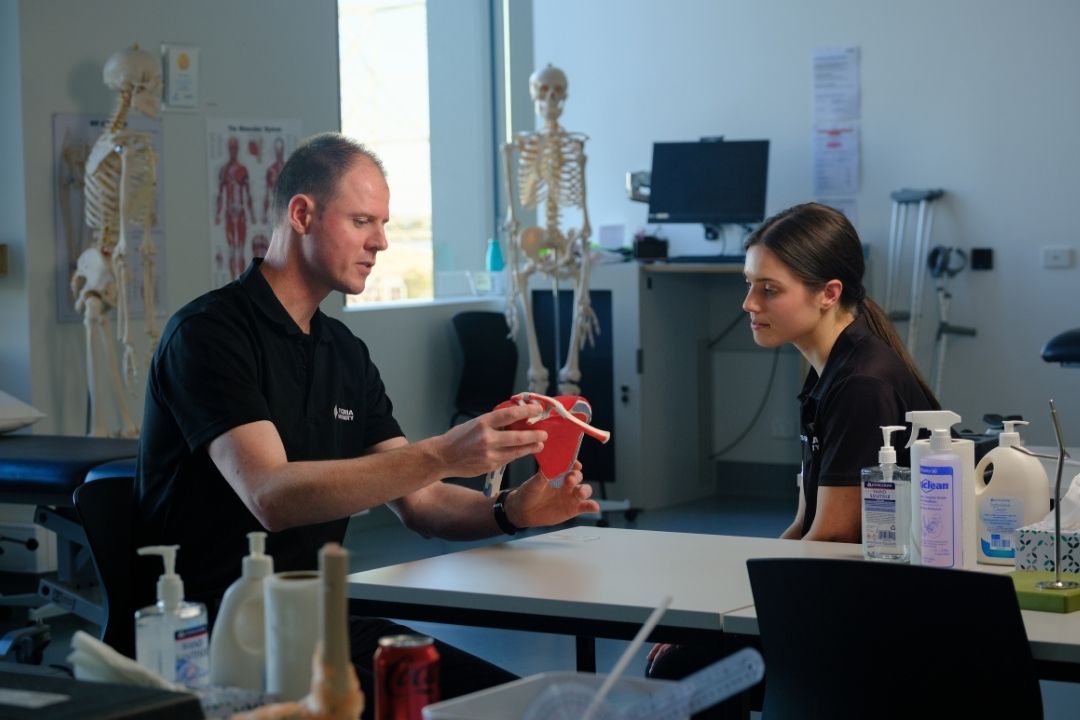 Physiotherapy teacher and student discussing anatomy