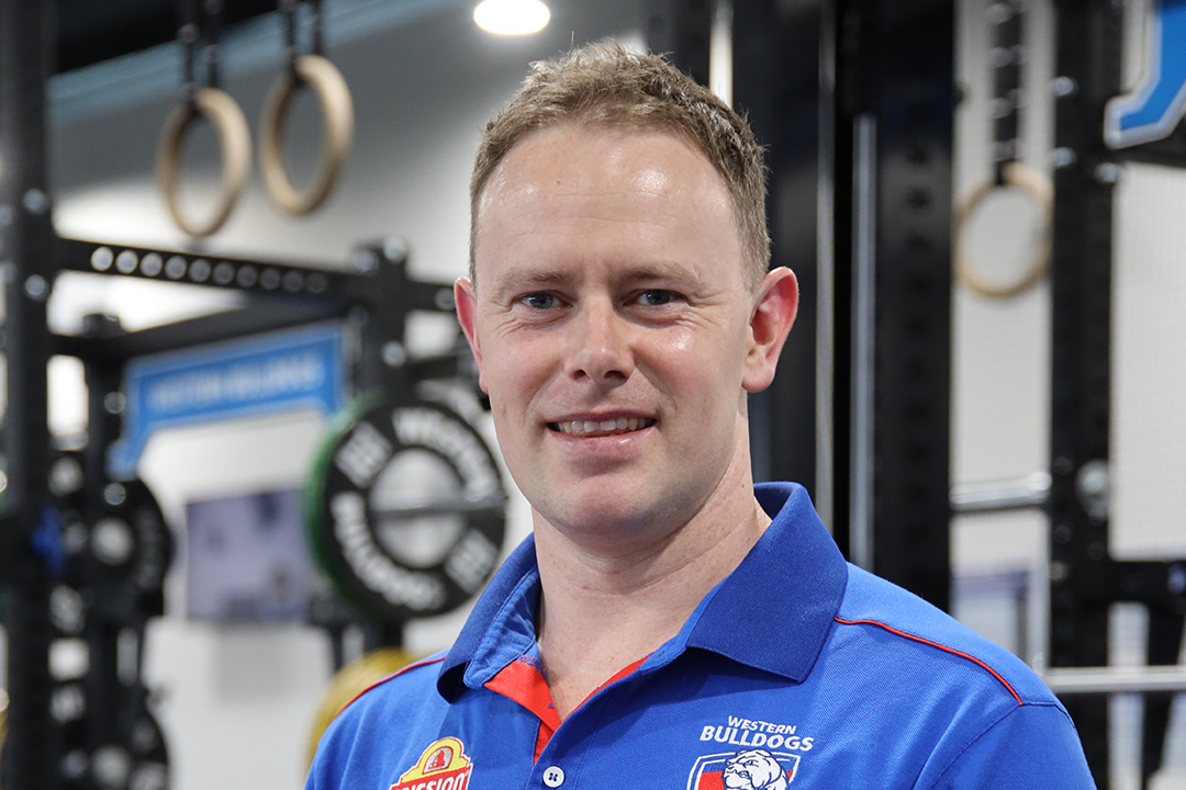 VU graduate Tim standing in front of gym equipment