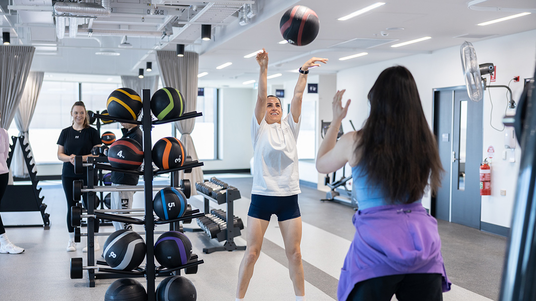 A white, bright, large room with exercise equipment and people exercising