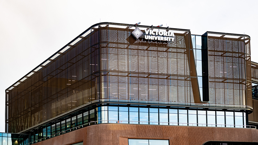A large modern glass and wood building with Victoria University signage