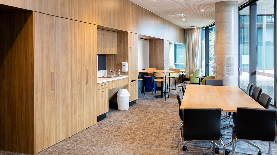 A clean wood-look kitchenette and dining area with floor-to-ceiling glass windows