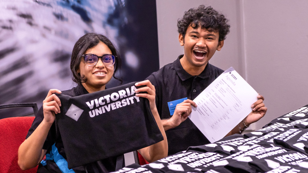  Smiling staff hold Victoria University branded merch