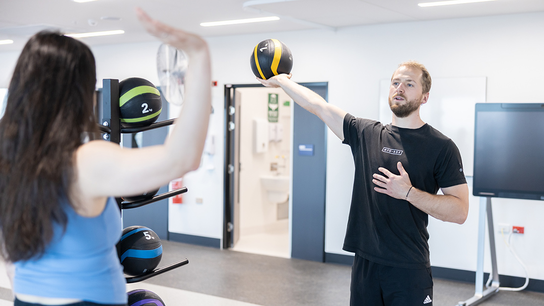 A young man in an exercise studio demonstrates exercises using equipement