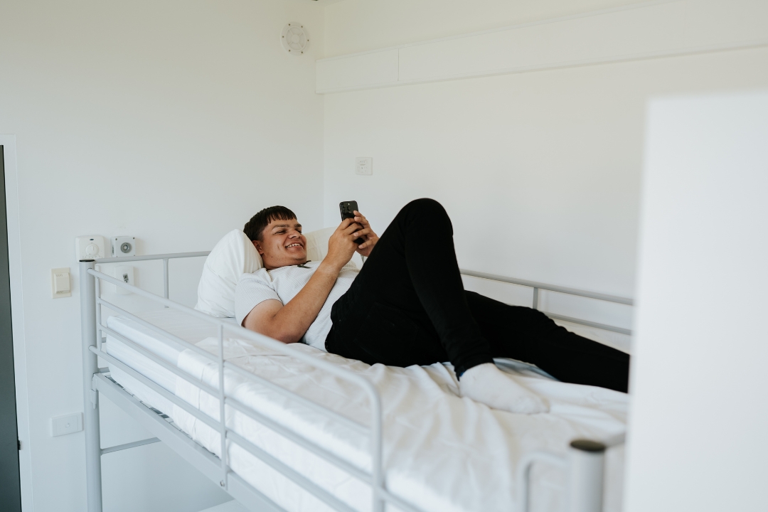 Altitude Hotel research participant lies in bed on phone
