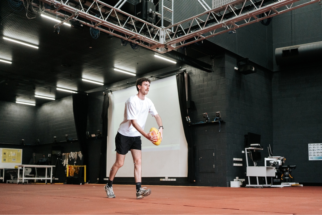 Student kicks a football in the biomechanics lab