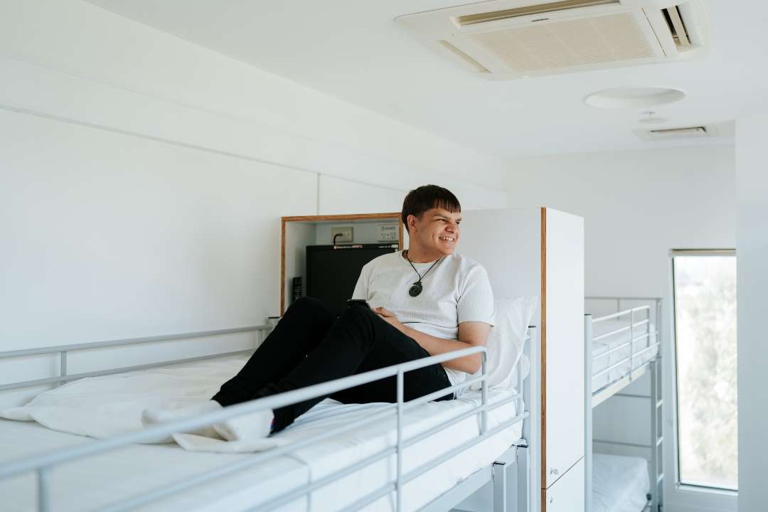 Young male research participant sitting in bed at the Altitude Hotel
