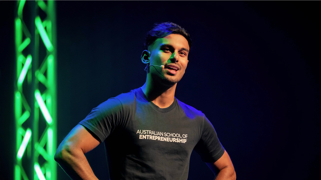 Man in black t-shirt speaking on stage.