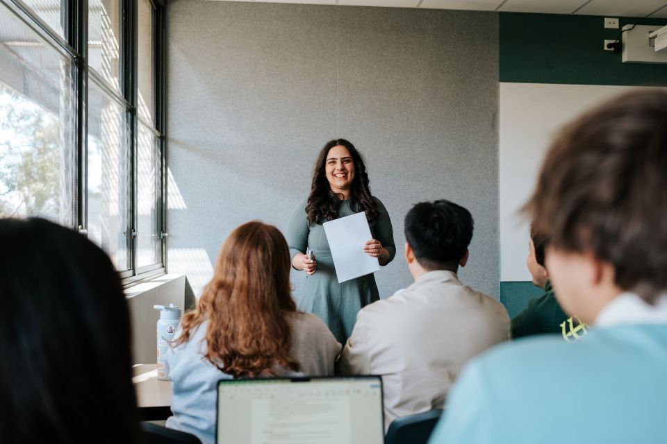 Smiling student presenting in front of classroom of peers