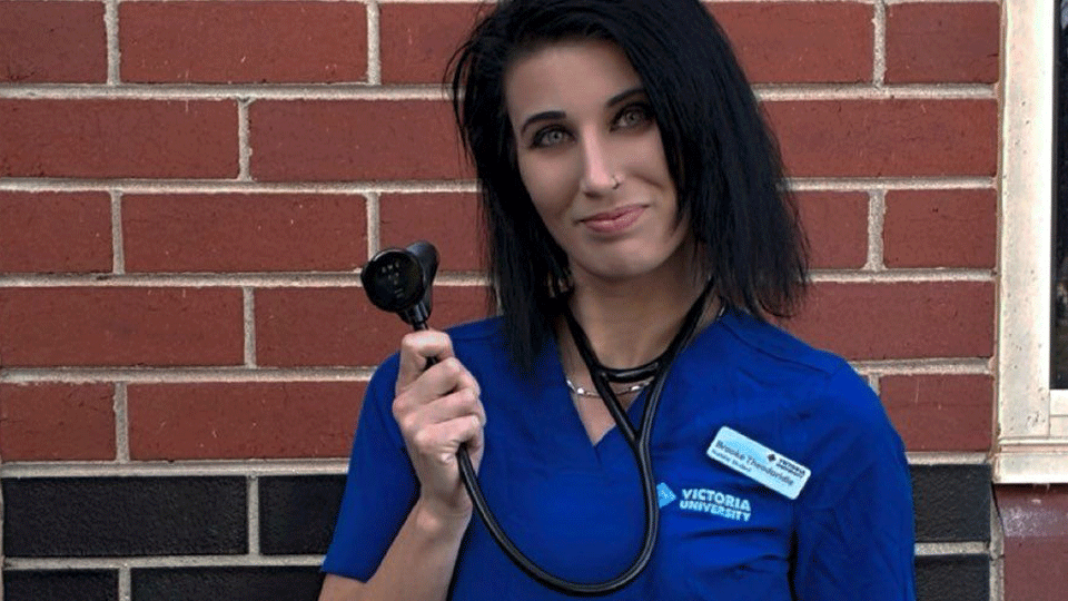 Young woman in a Victoria University nursing uniform and sethoscope, with