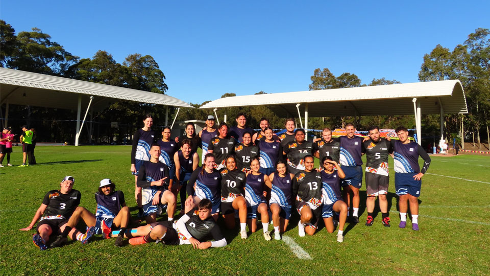 VU team and another competing university gather for a team photo after a touch football game, on the grounds at the University of Newcastle