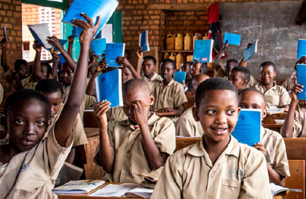 Group of Afrtican school children, in class, wearing uniforms, smiling and holding books